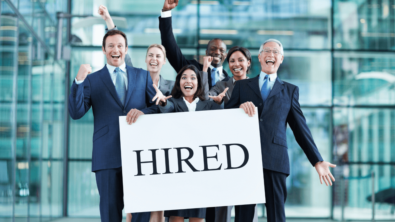 Office team holding a "hired" sign