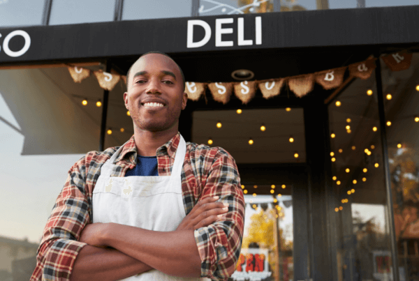 Business owner standing in front of his deli shop