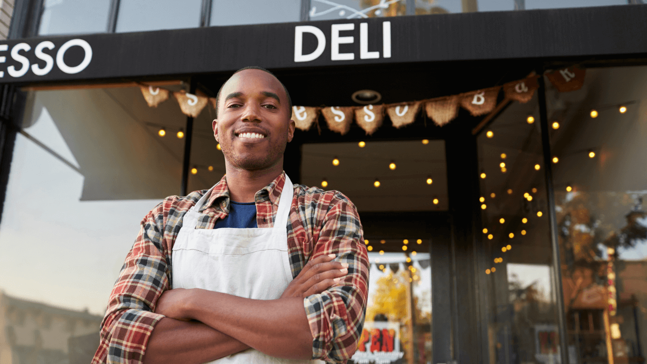 Business owner standing in front of his deli shop