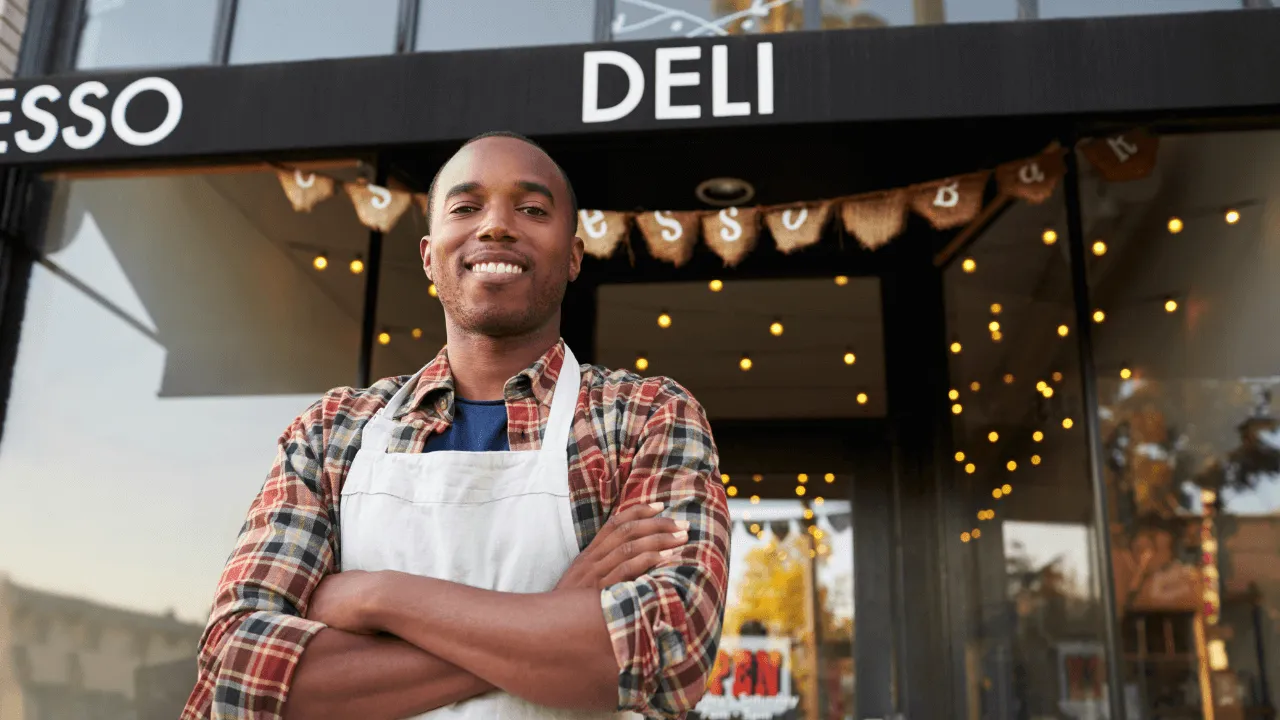 Business owner standing in front of his deli shop