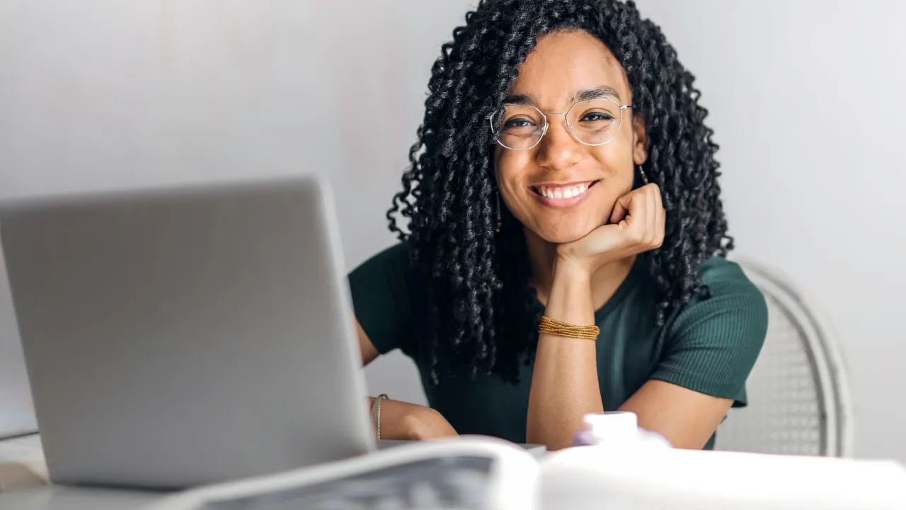 A woman smiling with her laptop set in front of her
