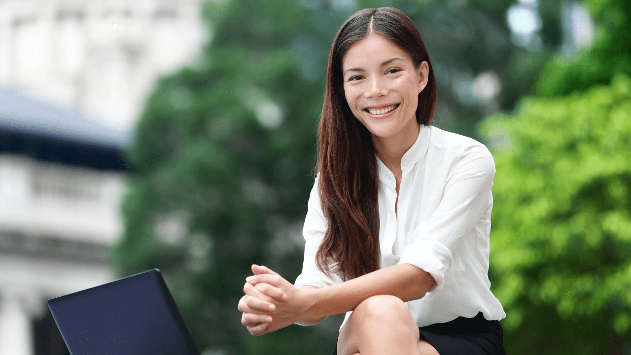 Business woman sitting outside smiling with her laptop