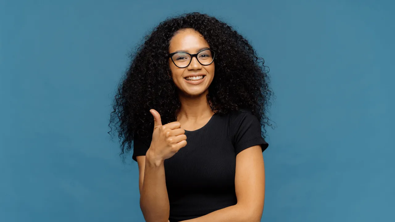 A woman smiling doing thumbs up for recent approval