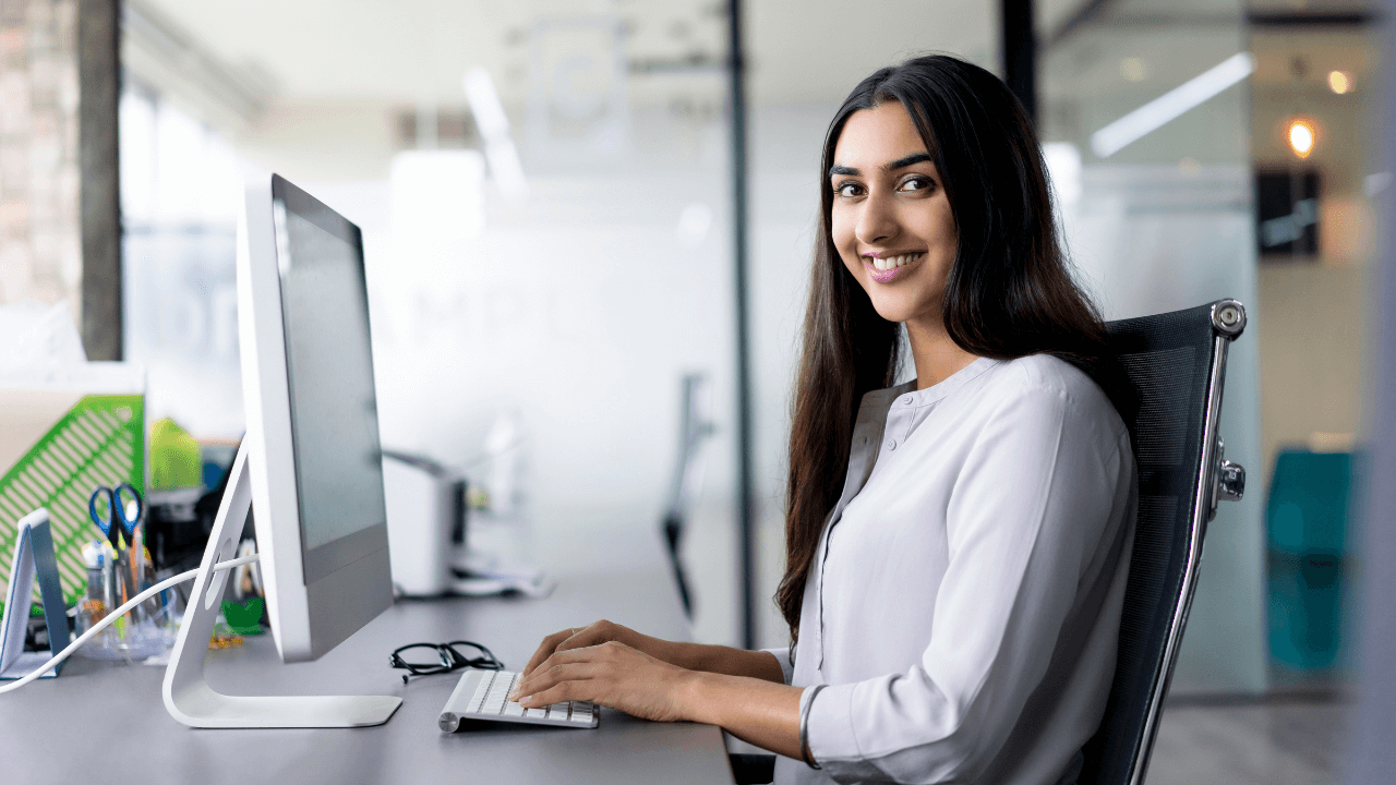 a woman seated at her desk while working on her desktop computer