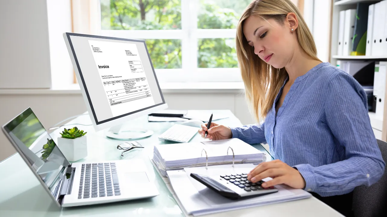 A woman working on invoicing at her office desk
