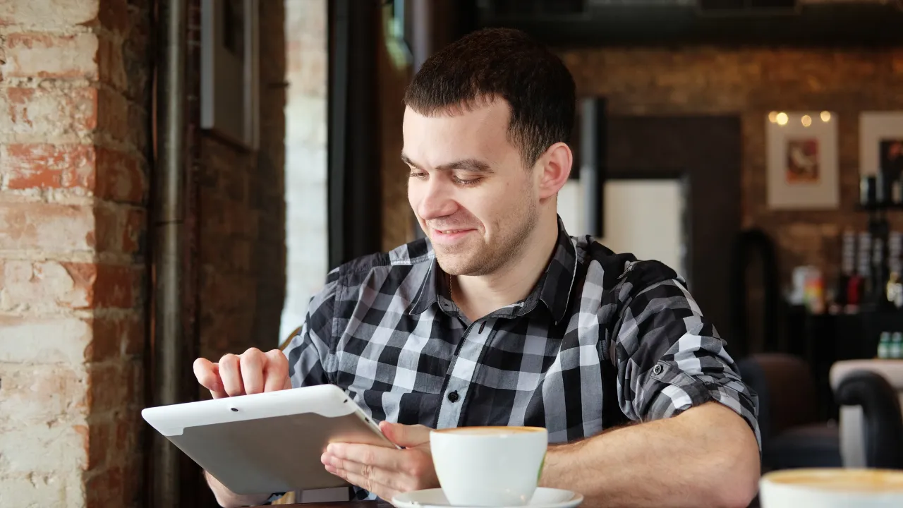 A man sitting in a cafe on his tablet