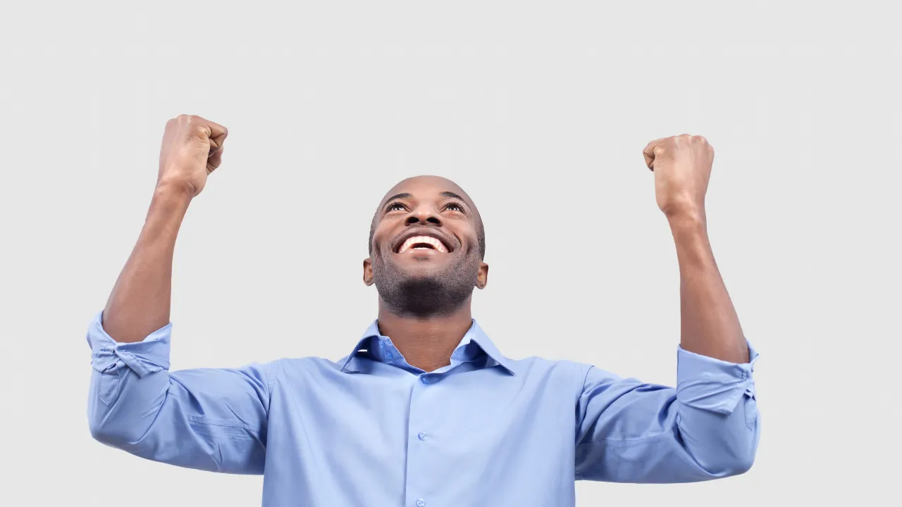 A man celebrating a win by throwing his arms up in triumph