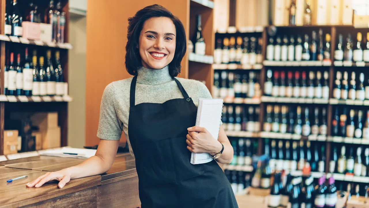 A business owner standing in her shop smiling while holding a notebook