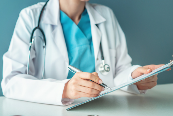 A doctor filling out a medical report on a clipboard | Scott Legal, P.C. A doctor filling out a medical report on a clipboard