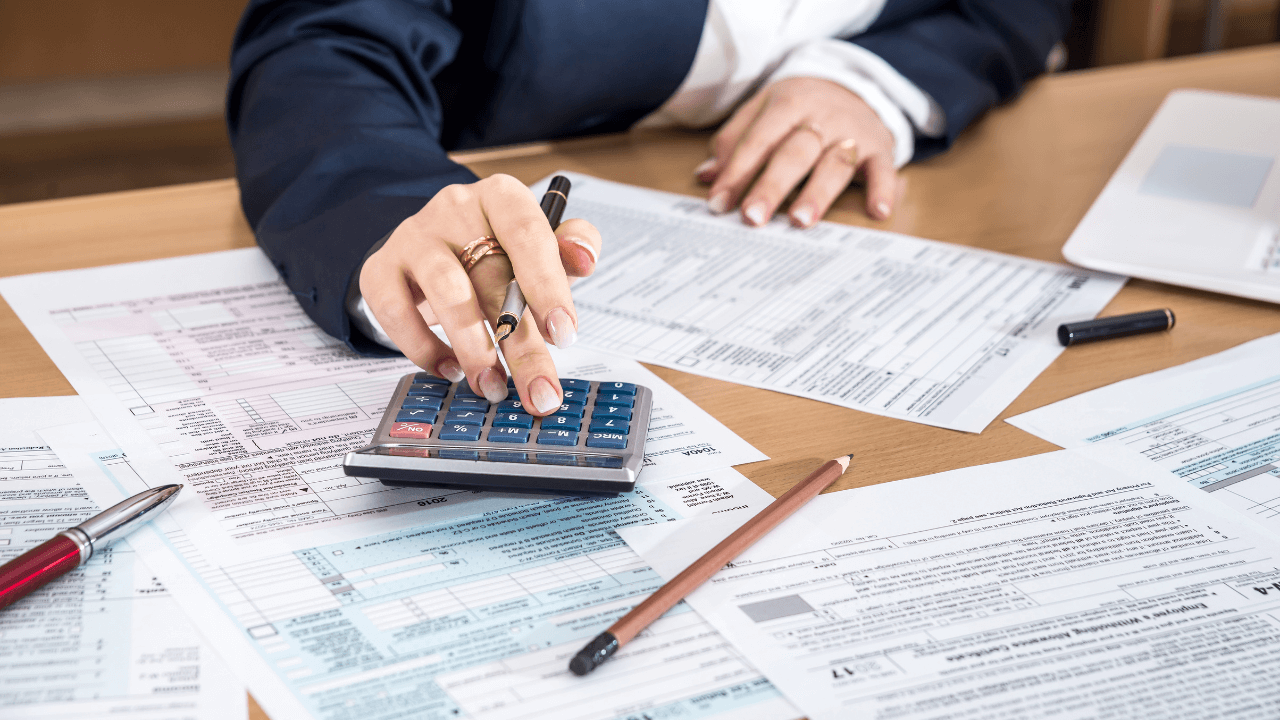 An accountant doing taxes on a desk full of financial documents