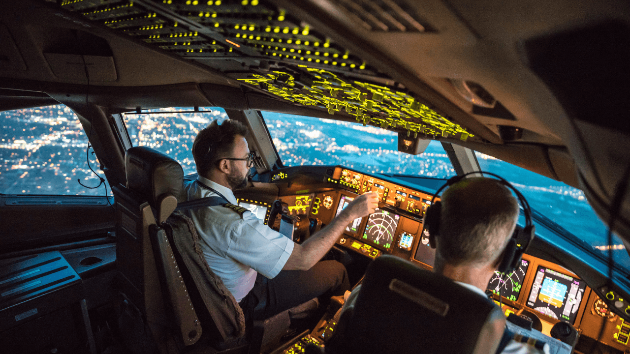 Two pilots sitting in the cockpit of an airplane that is in the air