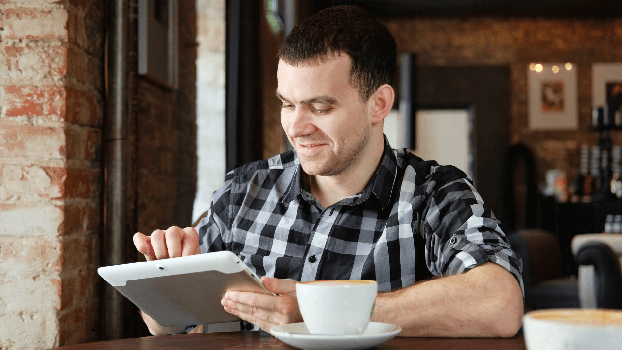 A man sitting in a cafe working on his tablet