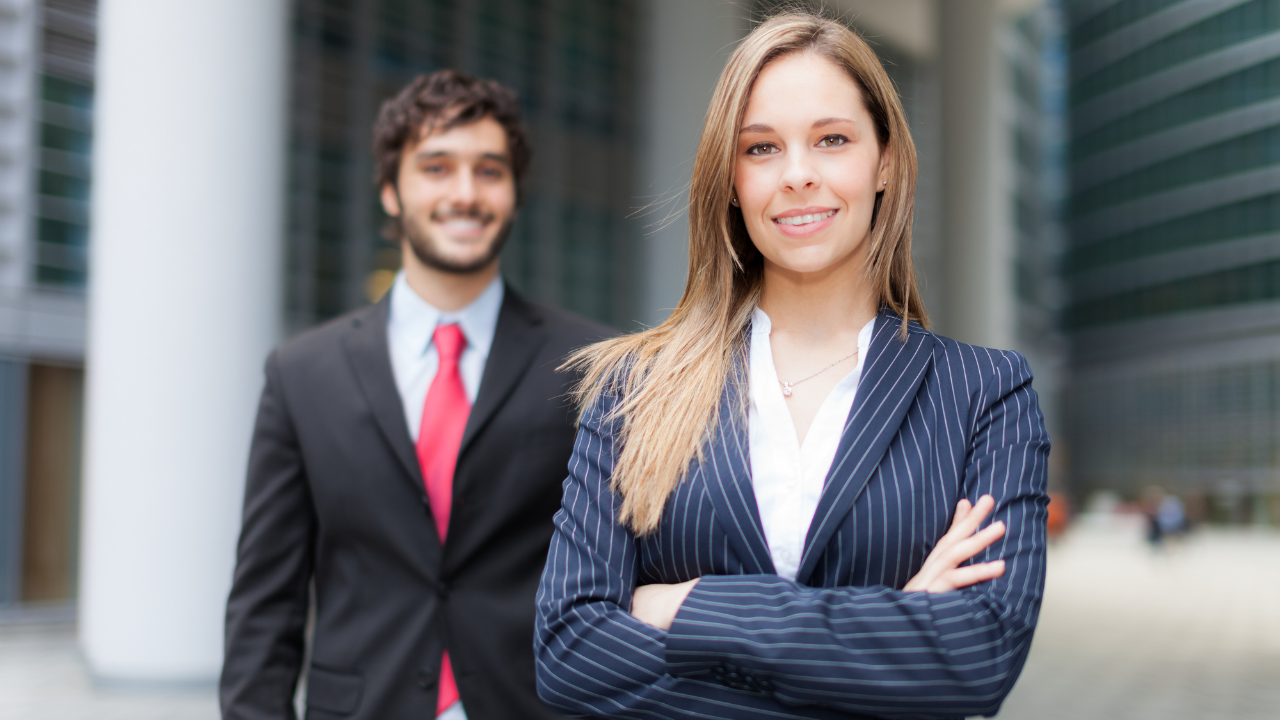 two partners in business attire standing outside their workplace