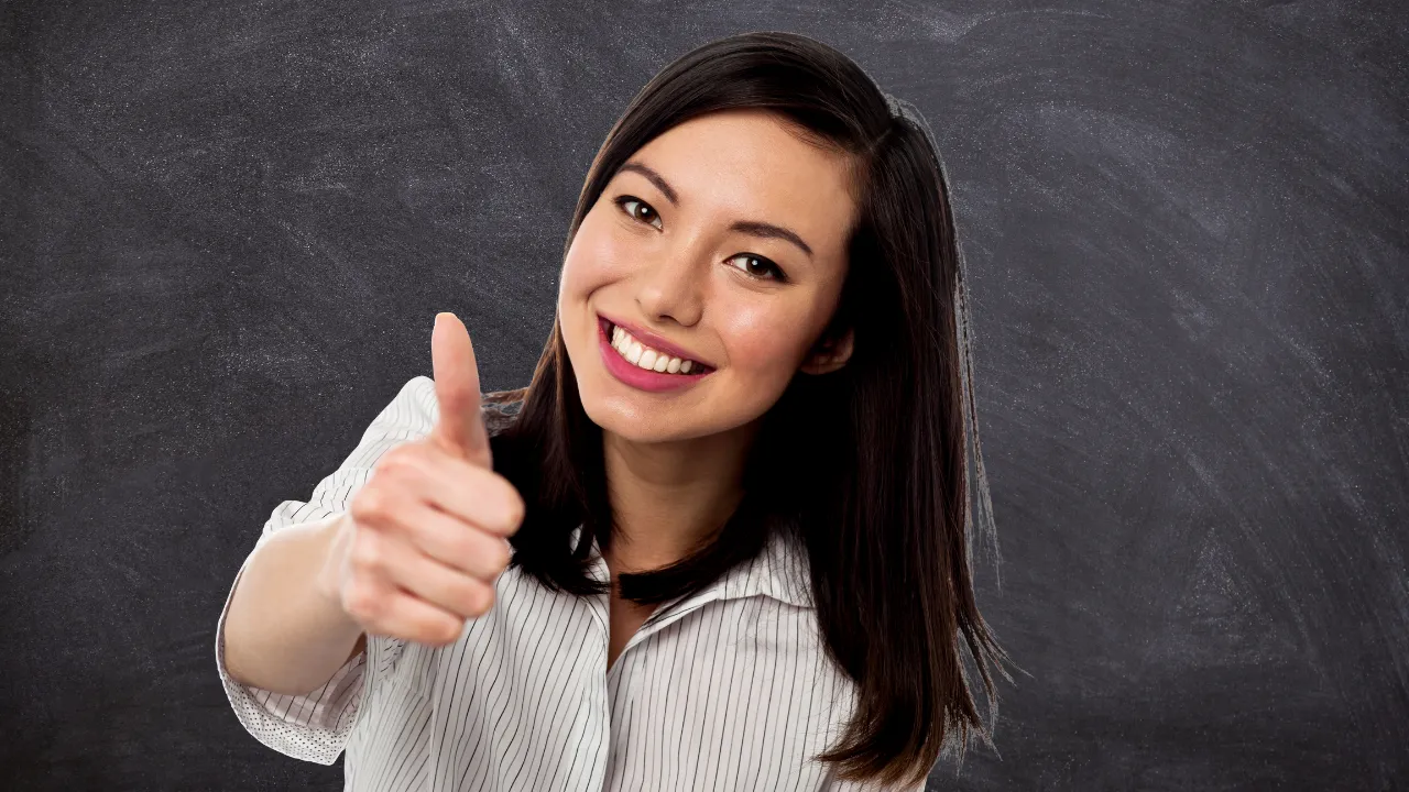 A woman smiling while indicating a thumbs up