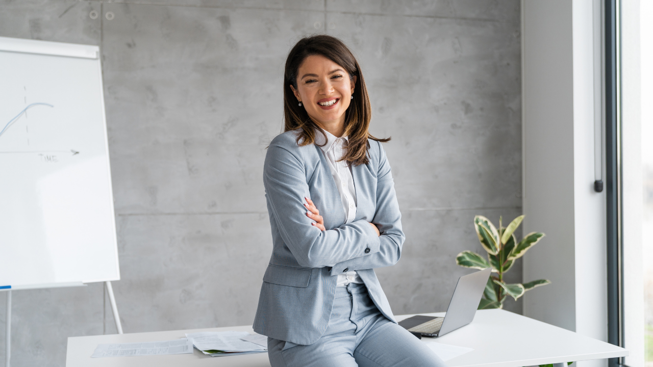 A business woman and entrepreneur sitting in her office smiling with her arms crossed