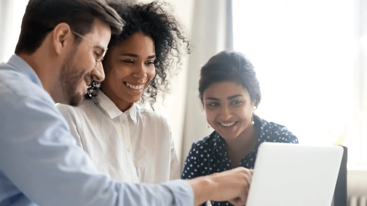 A group of 3 people mentoring each other around a presentation on a laptop