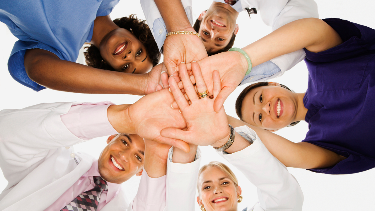 A group of healthcare workers joining hands in cooperation