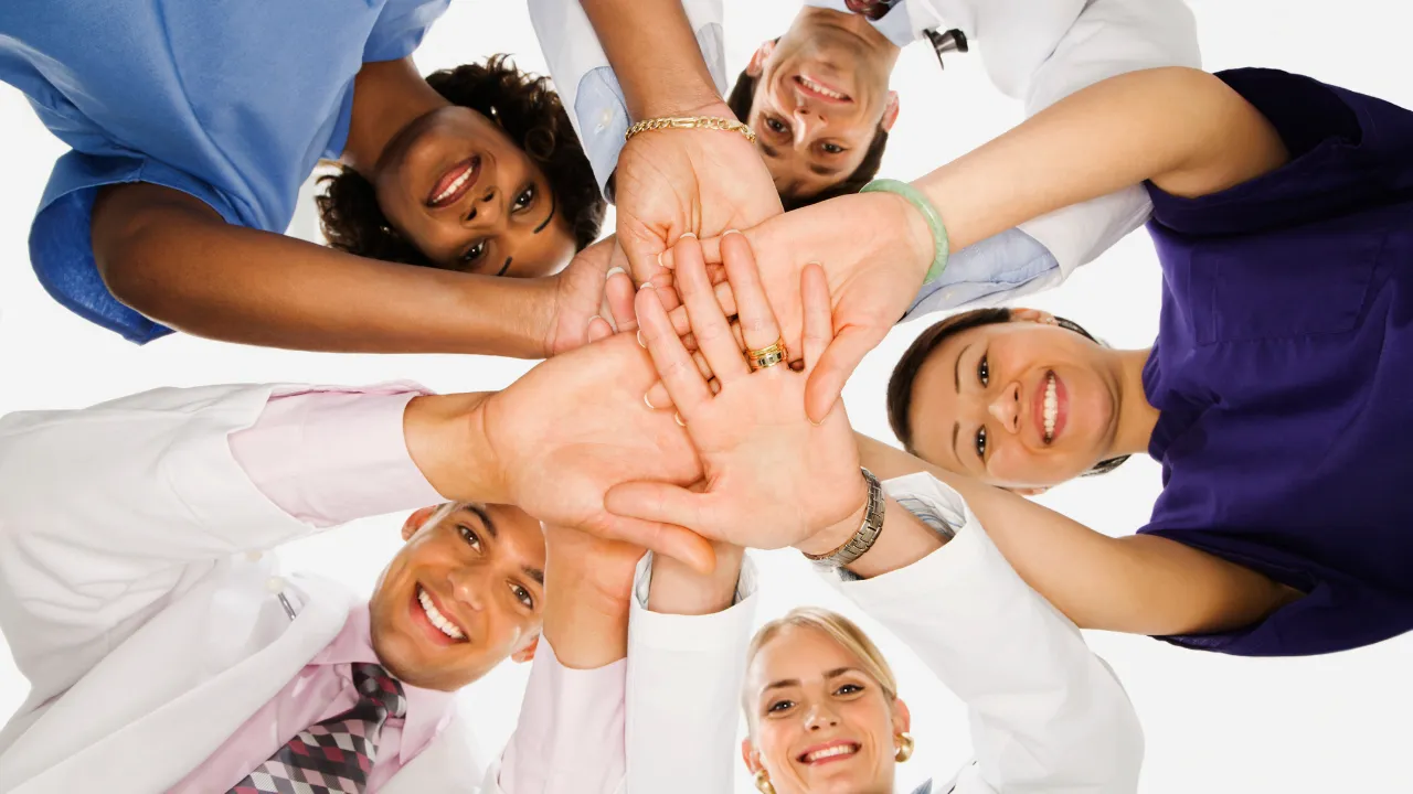 A group of healthcare workers joining hands in cooperation
