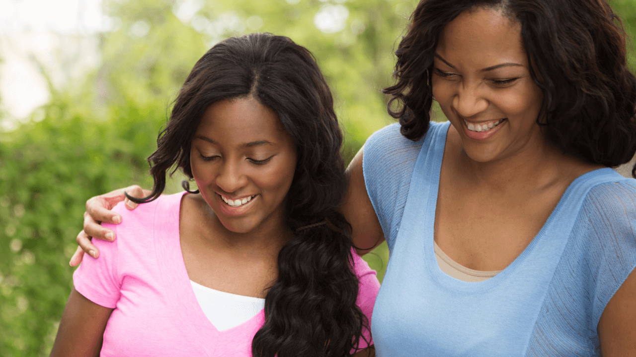 A mother and daughter walking in a park while smiling