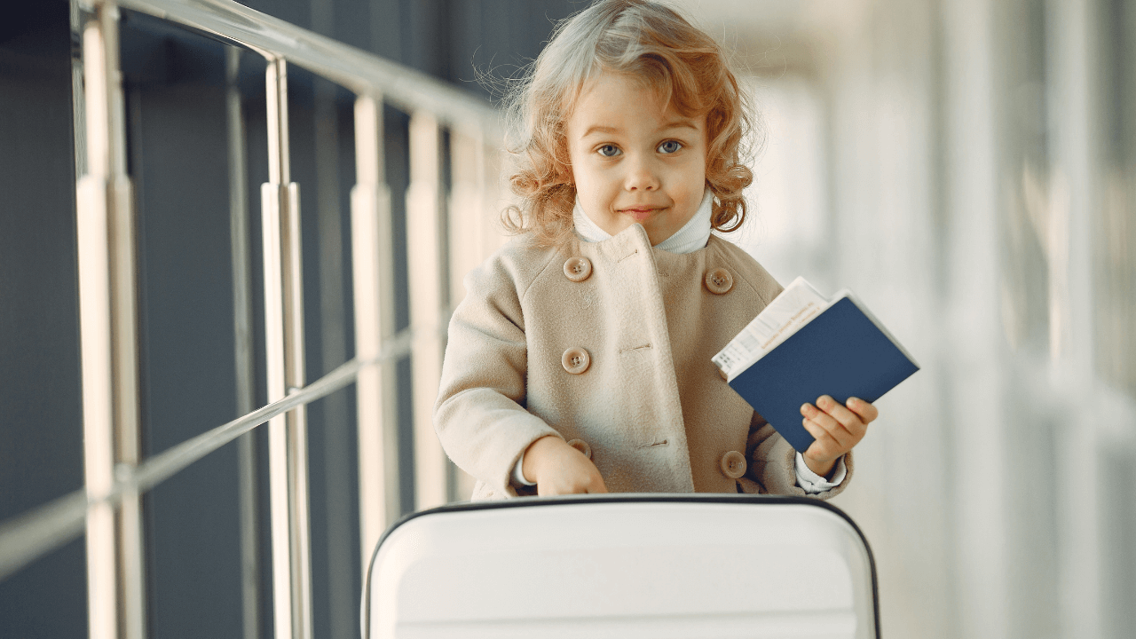 A little girl in the airport holding a passport and luggage