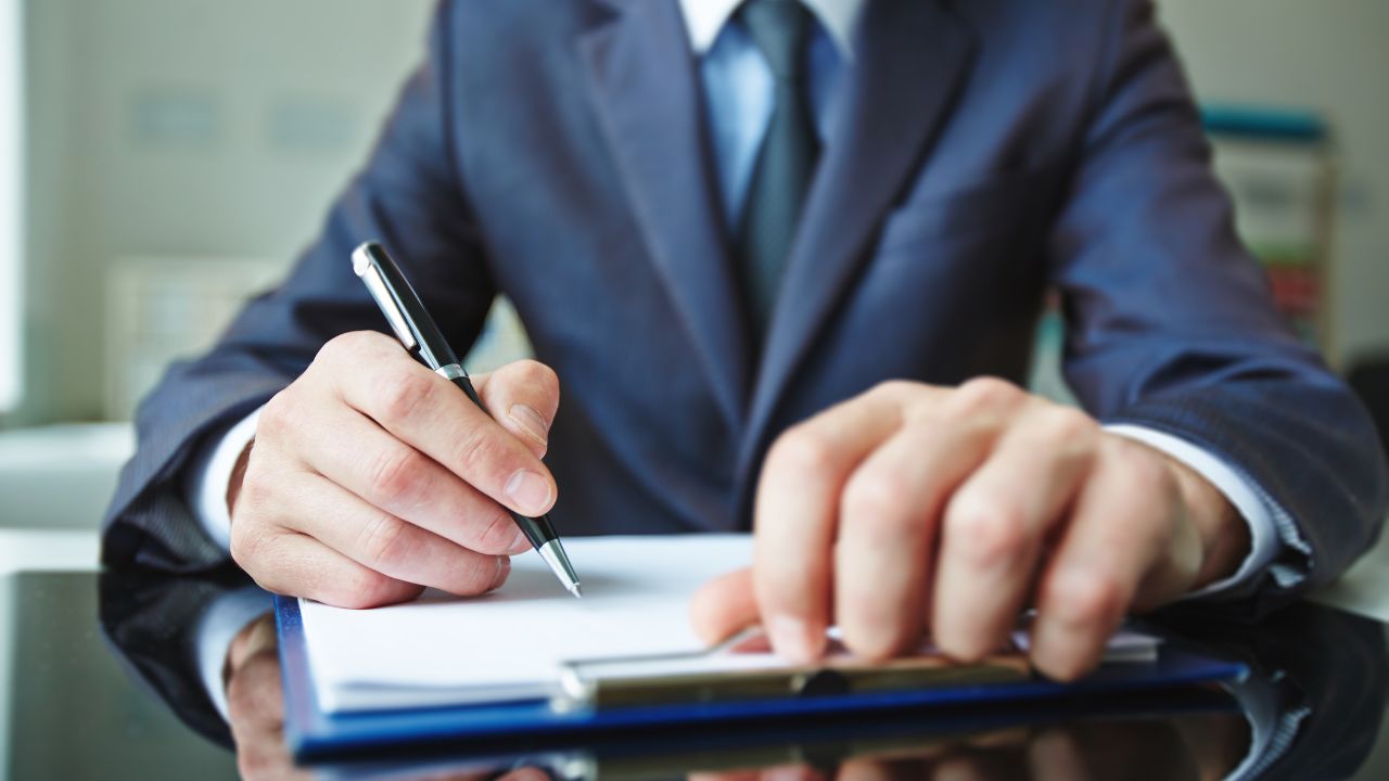 A man in a suit getting ready to sign some paperwork