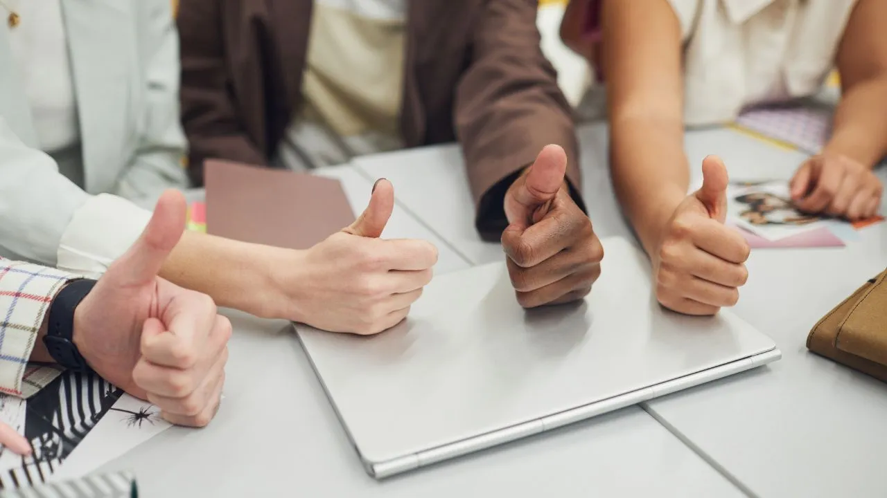 Four people giving thumbs up while in the office at work