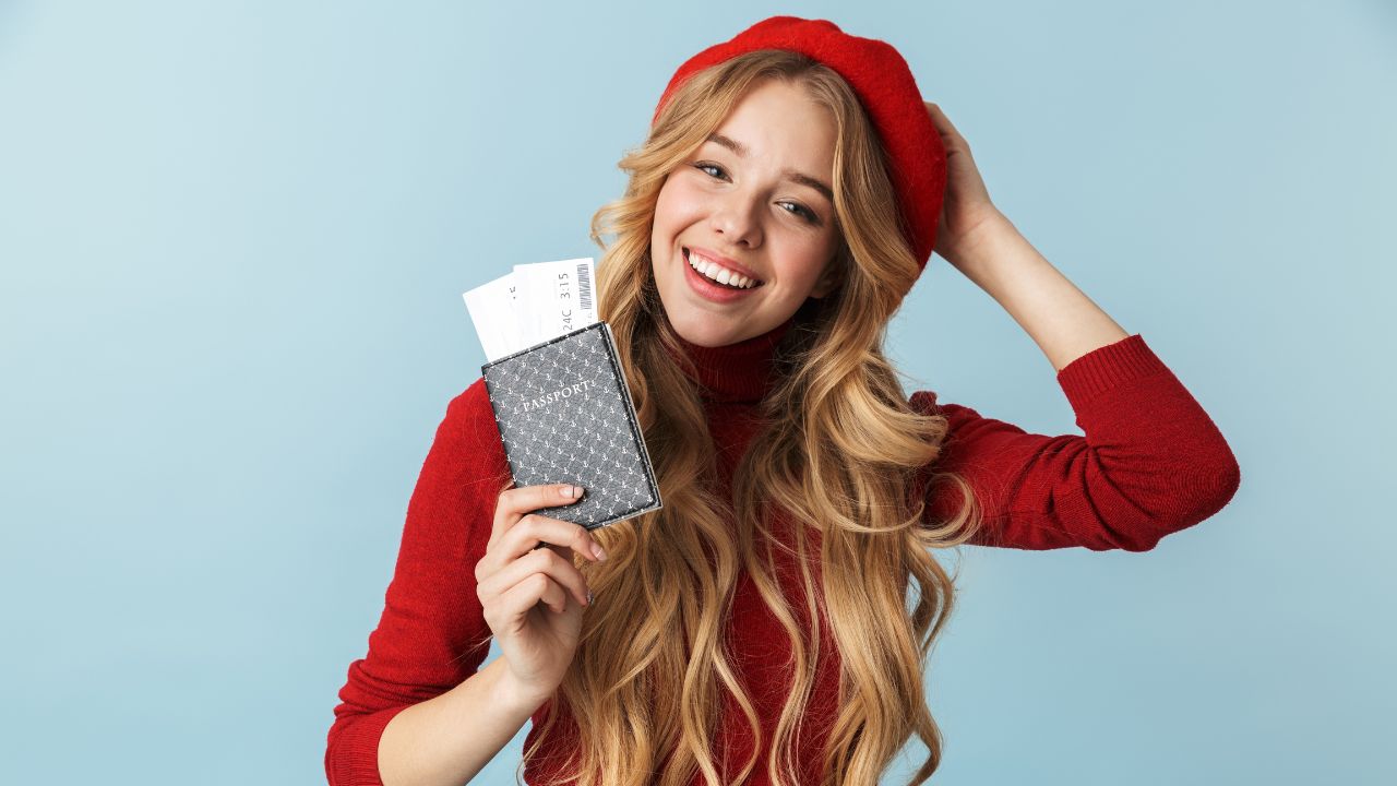 a happy woman holding her passport in preparation to travel