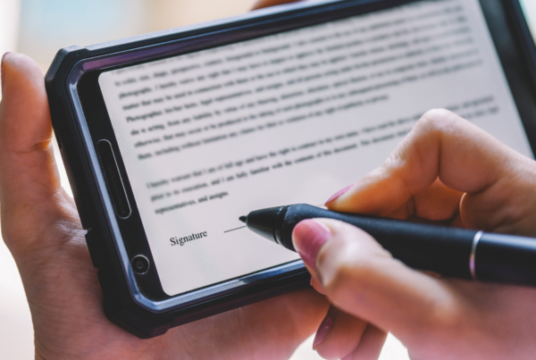 A man or woman holding a tablet and signing electronically