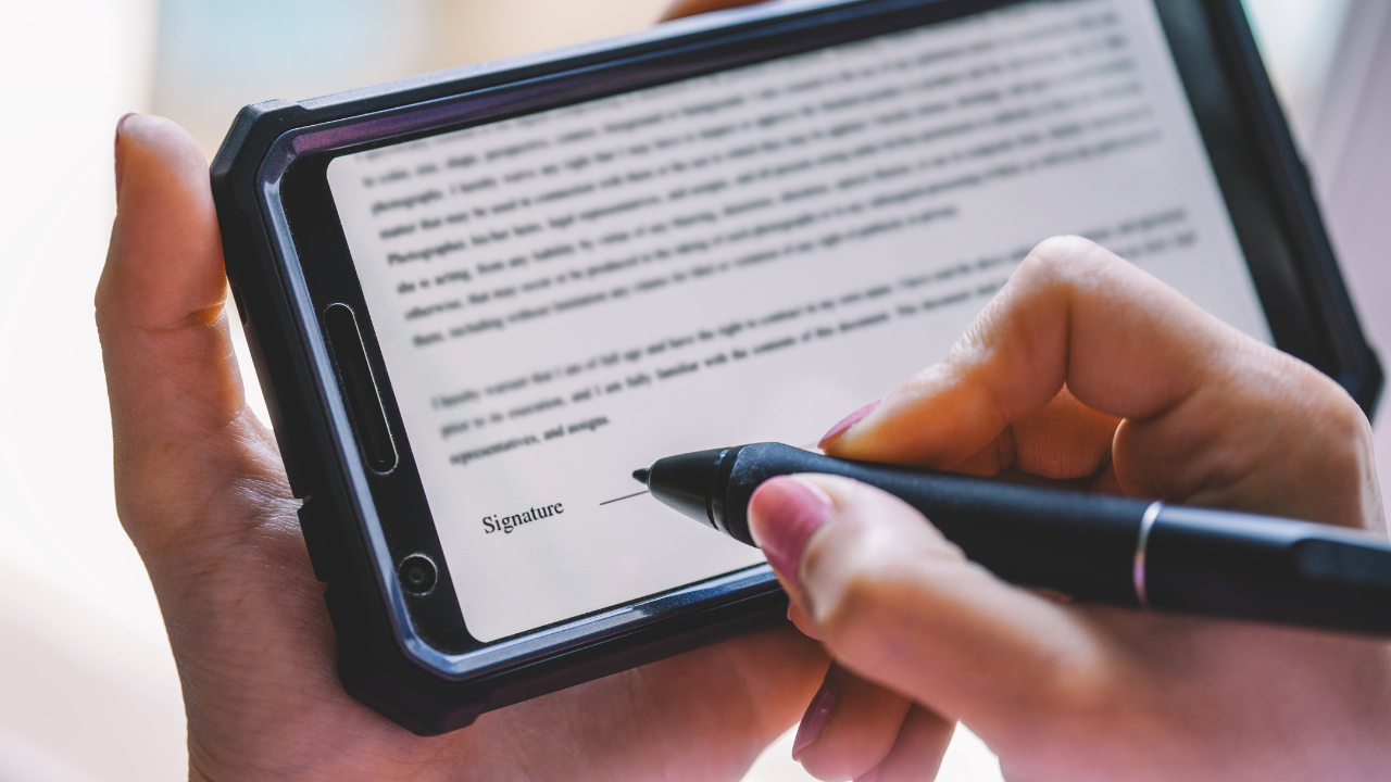 A man or woman holding a tablet and signing electronically