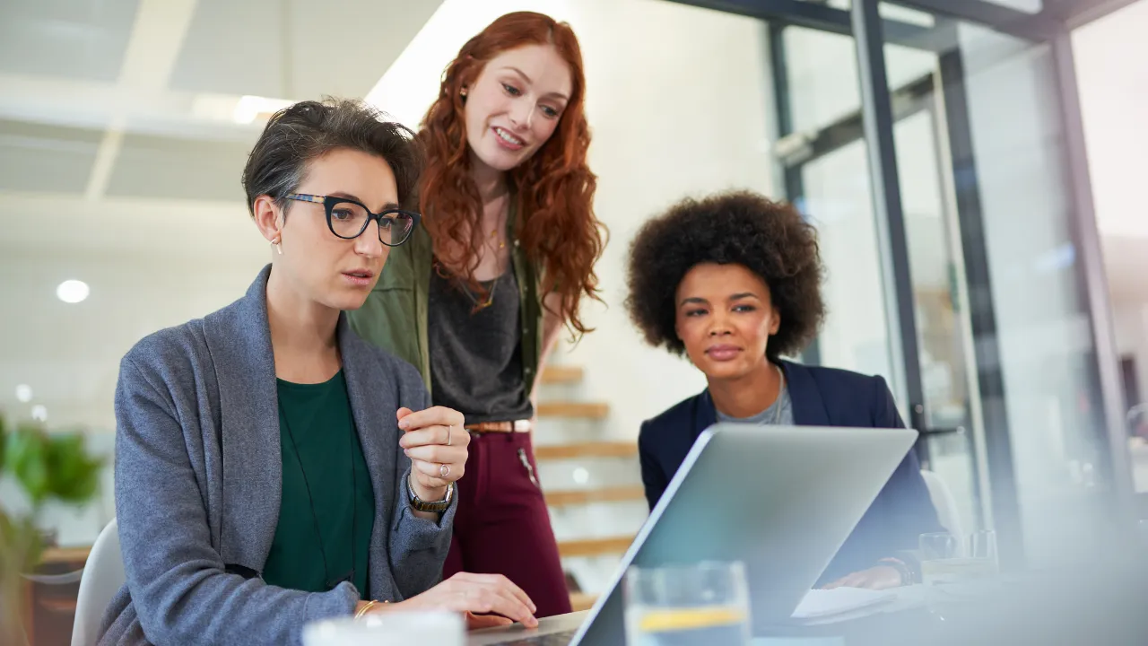 3 workmates working together while gathered around a laptop