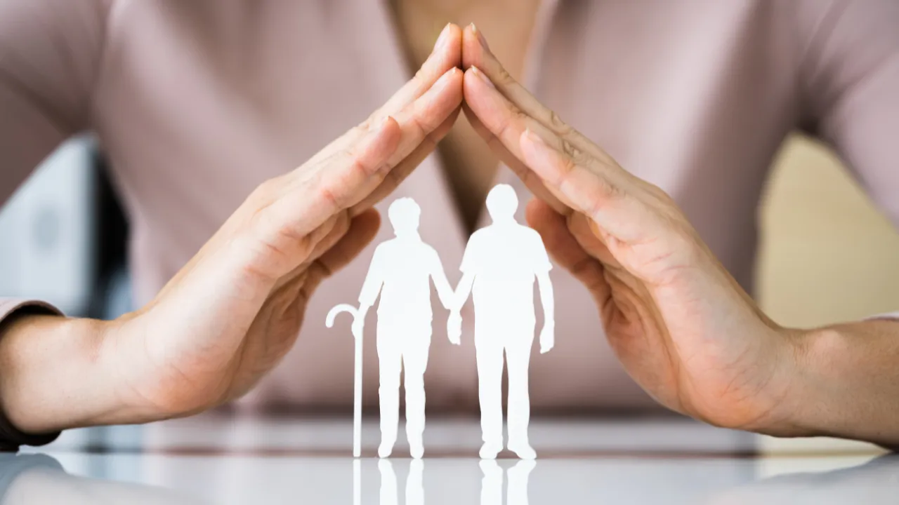 a hand protecting a paper cut out of a man and a woman