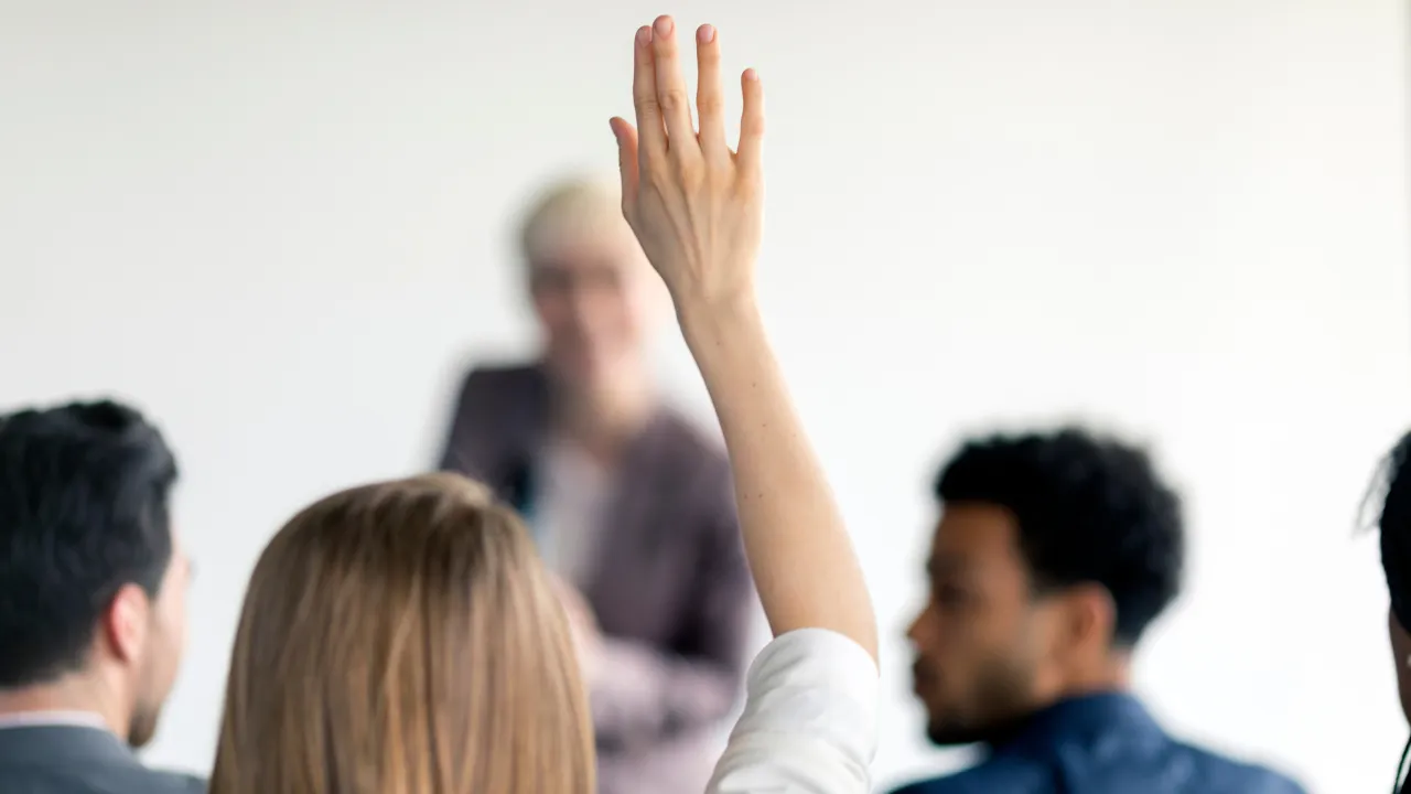 A woman raising her hand to ask a question