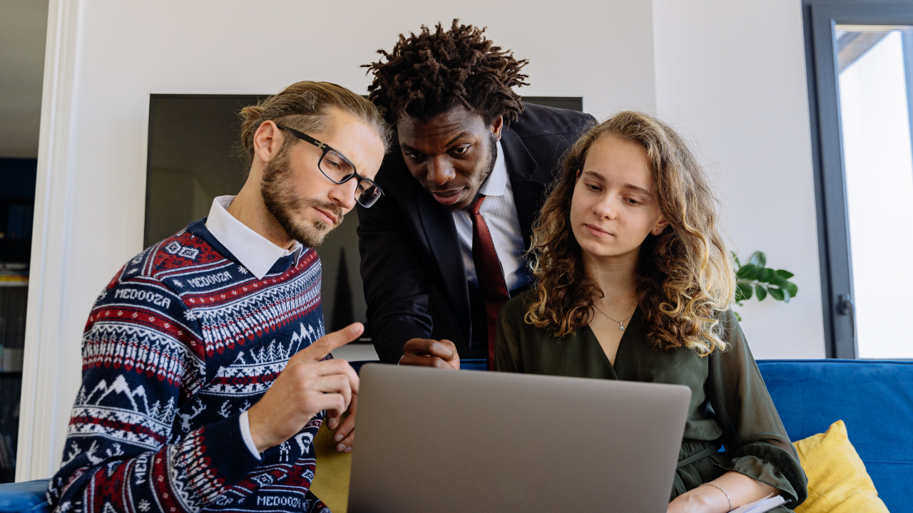 3 people gathered around a computer, looking at information