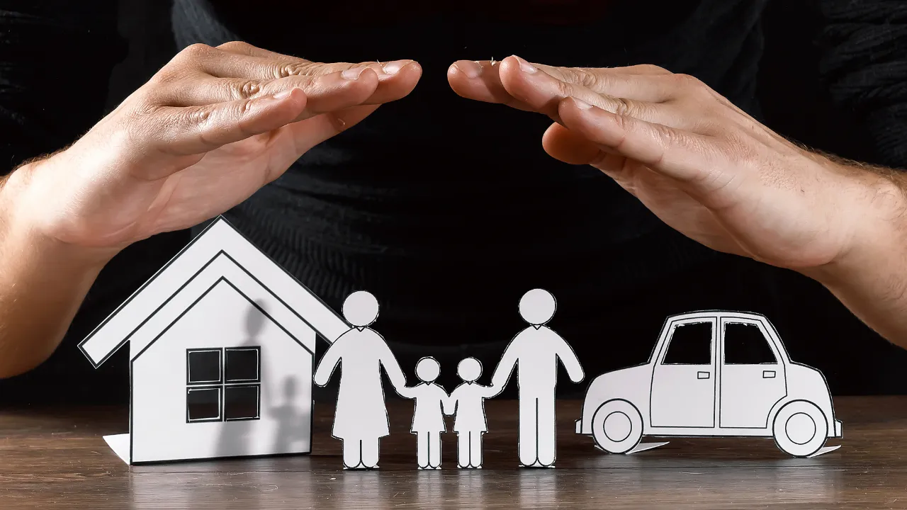 A hand protecting a cardboard cut out of a family