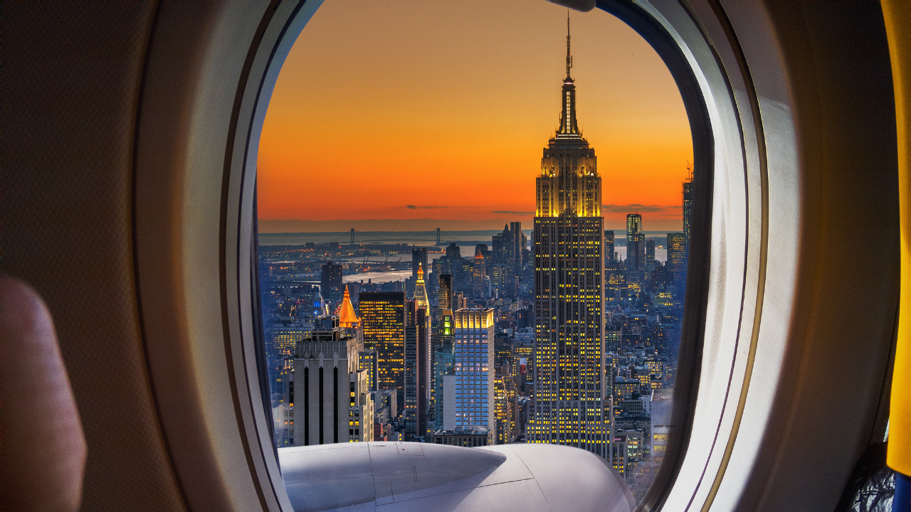 A traveller looking out an airplane window at a city view