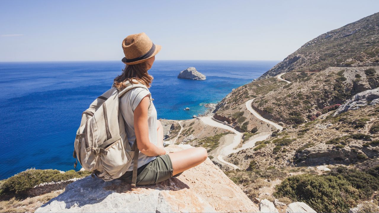 A woman sitting on a hill overlooking a travel destination