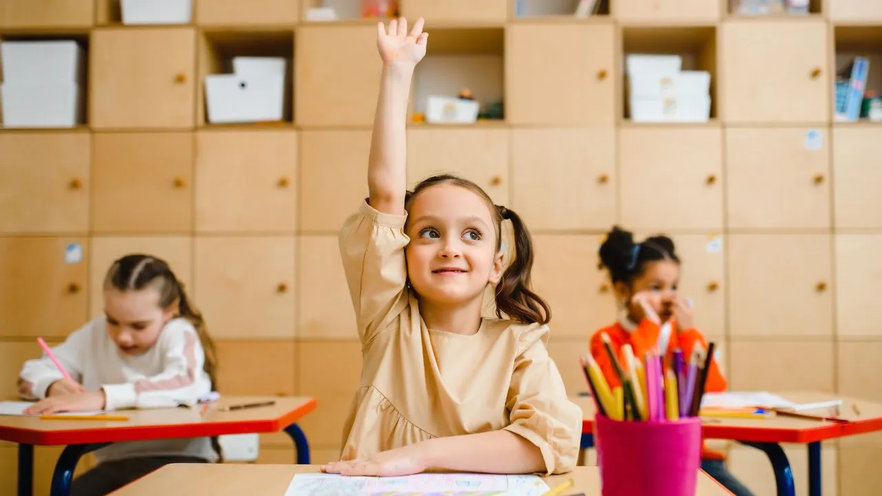 A child raising her hand to answer a question at school