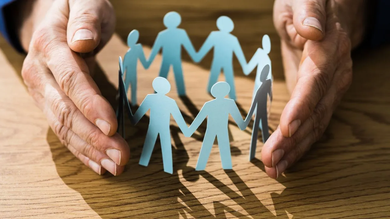 a hand protecting cut outs of people holding hands