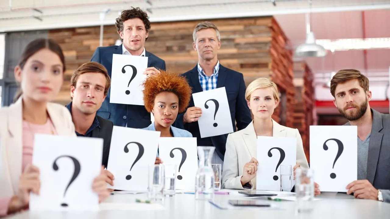 A bunch of people holding question marks while in the office