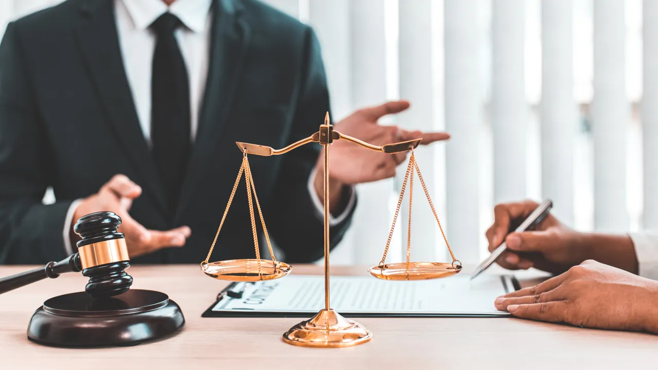 a lawyer in their office with the scales of justice and a gavel on their desk