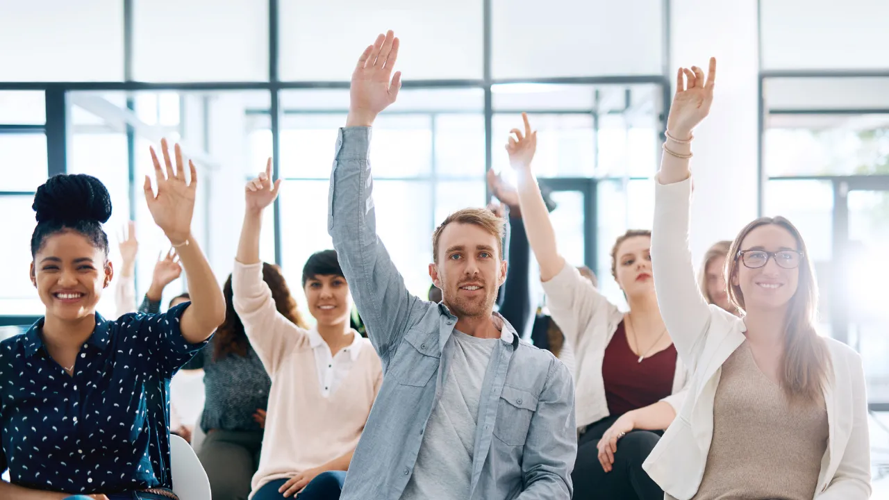 A group of people in a Q&A session raising their hands to ask questions