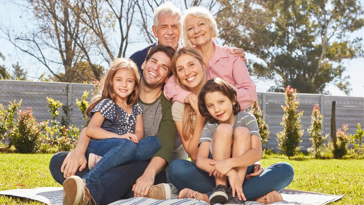 An extended family sitting on the grass at a park