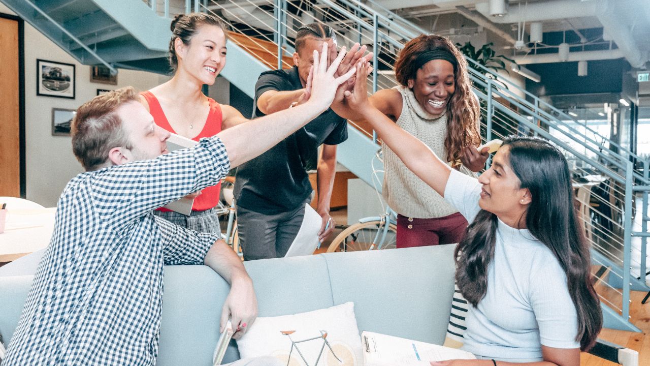 A group of people high fiving each other in celebration for good news