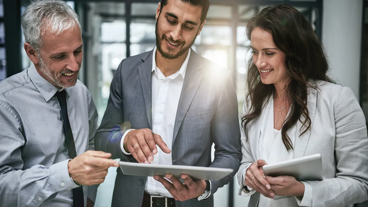 A group of professionals gathered to look at something on an ipad
