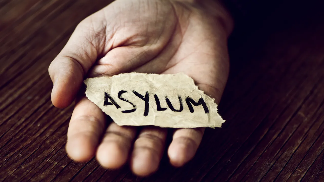 A man holding a paper that says "asylum" in his hand