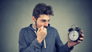 A man anxiously holding an alarm clock