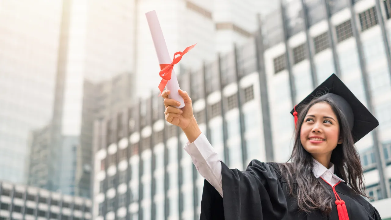 A graduate holding up a bachelor's degree