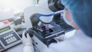 A researcher looking at something under a microscope