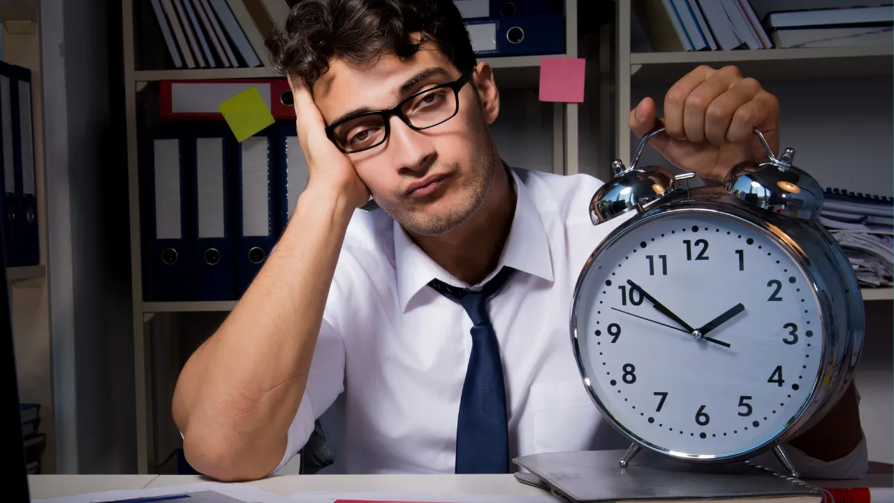 A man holding a clock to demonstrate delays