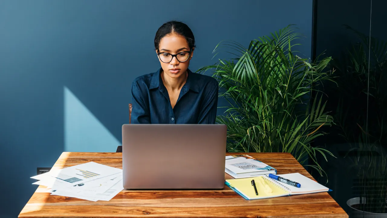 A woman working on her laptop at a desk in her home